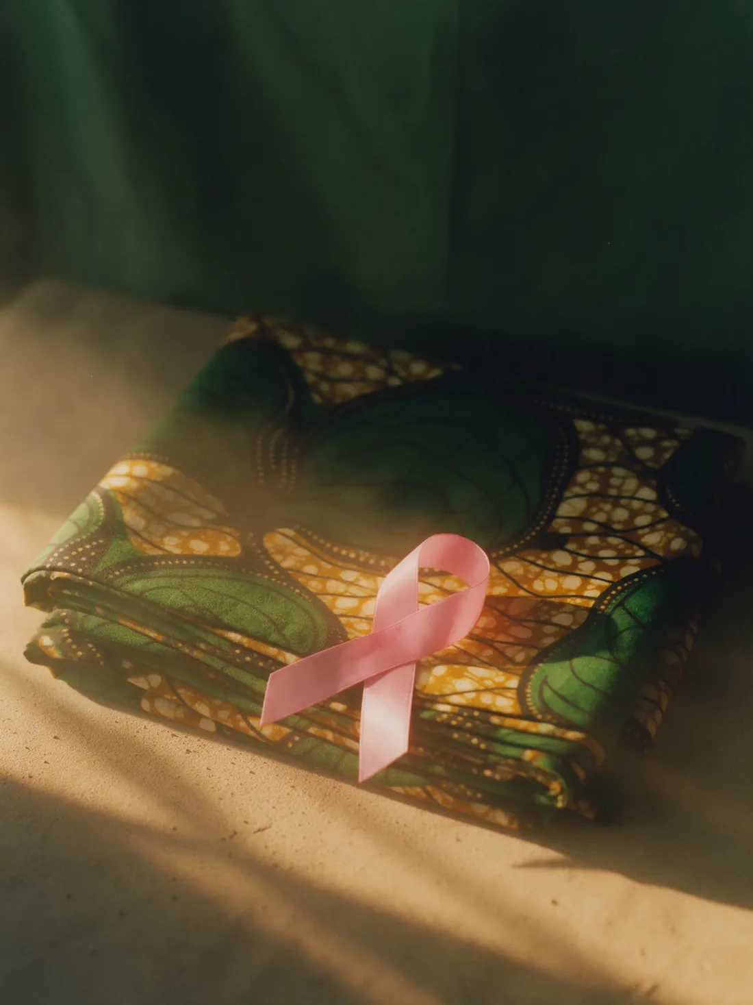 Un ruban rose de sensibilisation posé sur un pagne en wax plié.